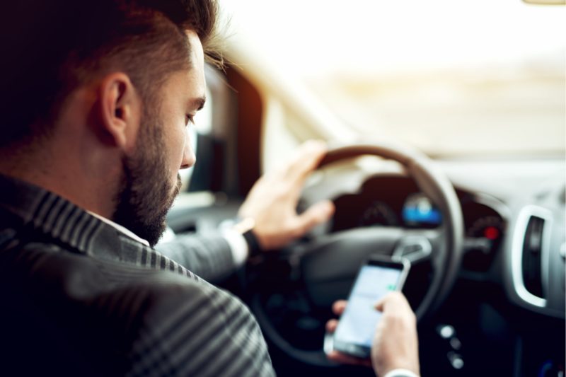 Man driving and looking at his smarthphone