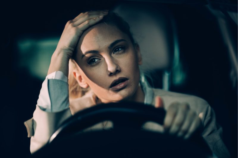 Frustated woman sitting in car with a hand on her head because she needs and SR22