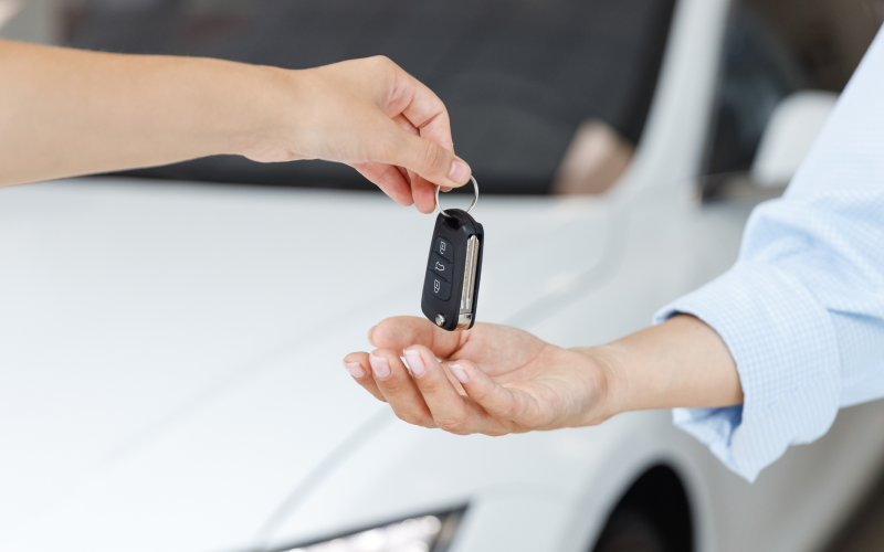Young person handing over the keys to his car to his friend