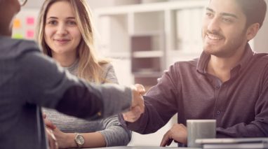 Young couple shaking hands with a female agent
