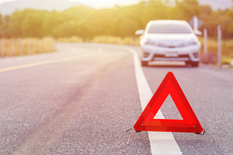 red emergency sign on the highway with a car on the background