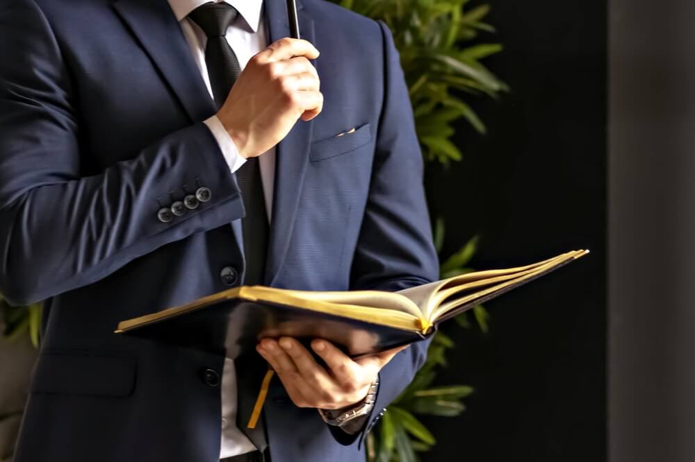 A business professional holding an open book, representing top sales books for agents to read.