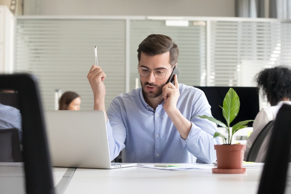 man on phone in front of computer