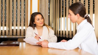 Two professionals review documents in a meeting, discussing marketing strategies to support business growth. Two professionals review documents in a meeting, discussing marketing strategies to support business growth.