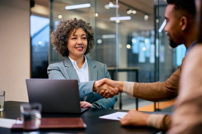 African American insurance agent shakes hands with male customer.