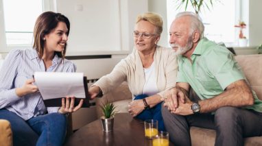 Young female insurance agent chats with couple from the boomer generation.