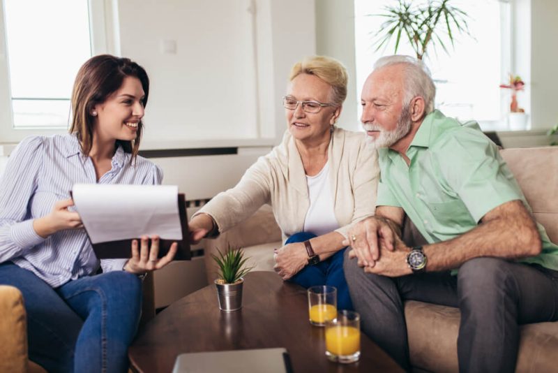 Young female insurance agent chats with couple from the boomer generation.