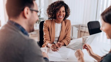 A female insurance agent laughs and chats with her clients.