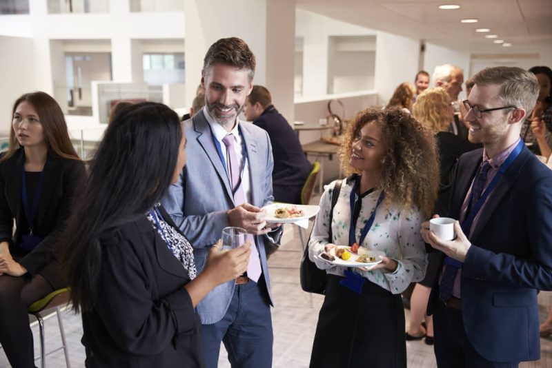 Group of independent insurance agents chatting during coffee break at conference.
