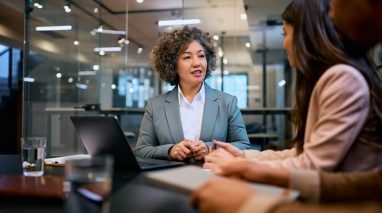 Female insurance agent talking to African American couple during a meeting in the office for an insurance client policy review.