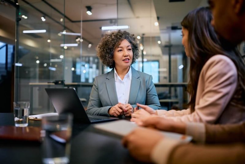 Female insurance agent talking to African American couple during a meeting in the office for an insurance client policy review.