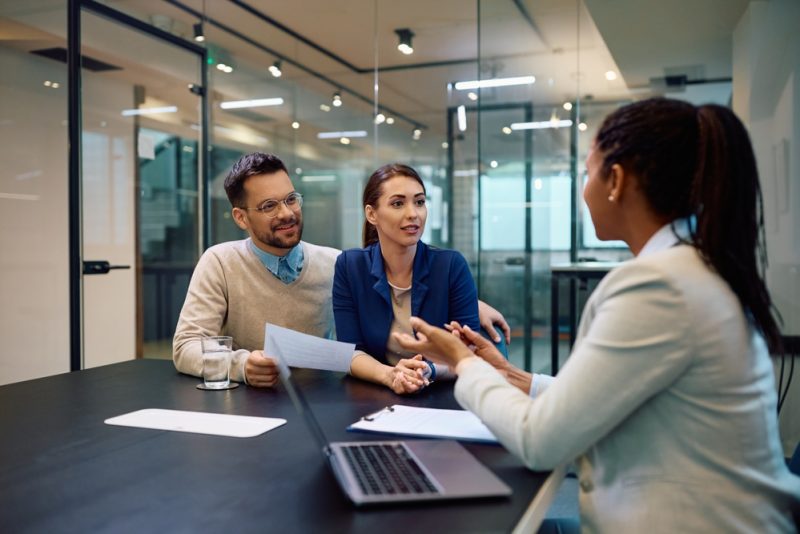 Young couple talking to their independent insurance agent during a meeting in the office.