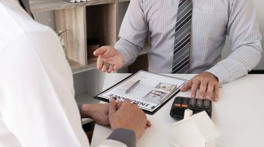 Agent,Calculate,House,Price,For,Take,The,Home,Insurance,And Insurance agent discussing coverage updates with a customer at a desk.