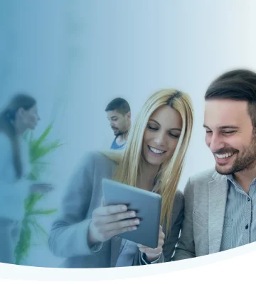 Smiling male and female insurance agent in an office viewing an iPad