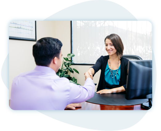 Businesswoman behind desk shaking hands with clients in front of window. Businesswoman behind desk shaking hands with clients in front of window.